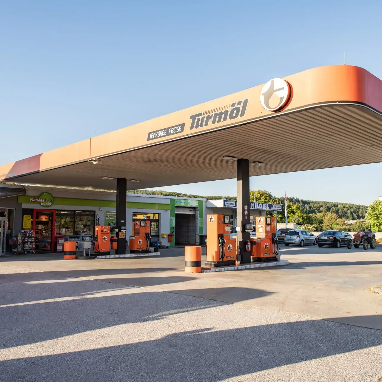Tankstelle der Marke Turmöl bei Tageslicht, mit mehreren Zapfsäulen und einem Shop im Hintergrund.
