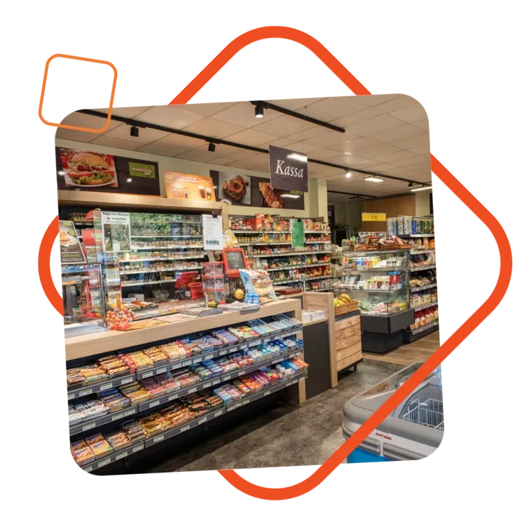 Innenansicht des Nah & Frisch Shops bei der Tankstelle Loibl, mit gut sortierten Regalen voller Snacks, Getränke und Lebensmittel an der Kassa – eingerahmt von einem dynamischen orangefarbenen Grafikrahmen.
