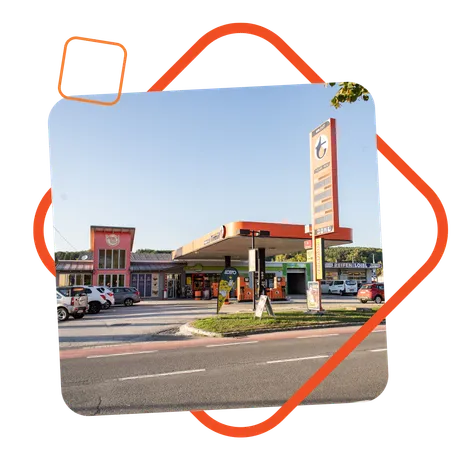 Außenansicht der Tankstelle Loibl in Piringsdorf, mit Turmöl-Zapfsäulen, einem gut sichtbaren Preisschild und angrenzendem Shopgebäude; eingerahmt von einem orangen grafischen Element.