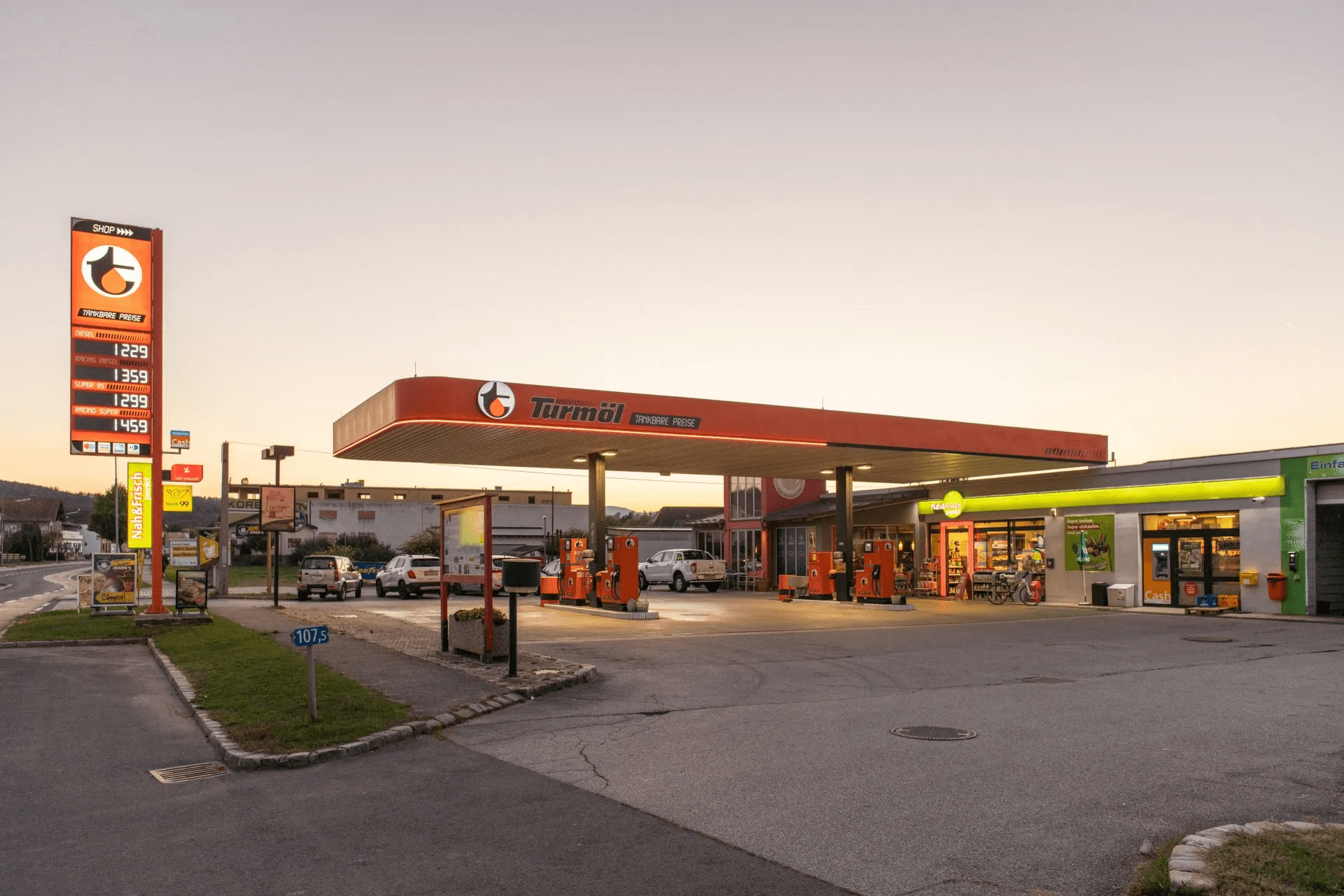 Turmöl Tankstelle Piringsdorf bei Sonnenuntergang mit Shop, Zapfsäulen und Preisschild.